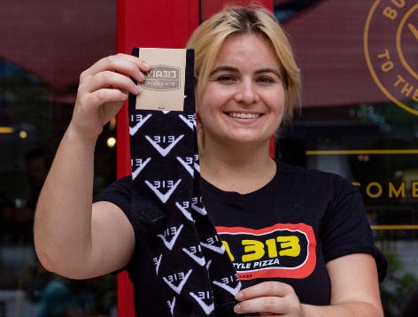 Viva313 black socks with logo step and repeat held by woman