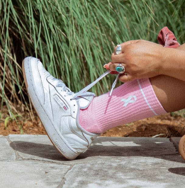 Woman tying her shoes wearing pink custom socks for breast cancer awareness