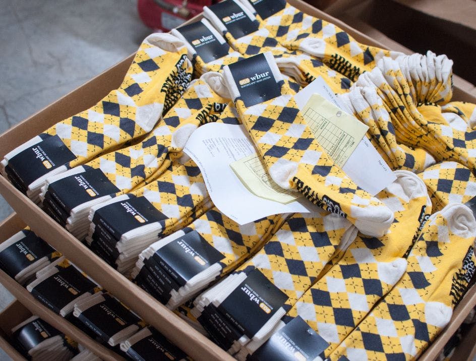 A bulk order of custom argyle socks for WBUR being fulfilled in a warehouse