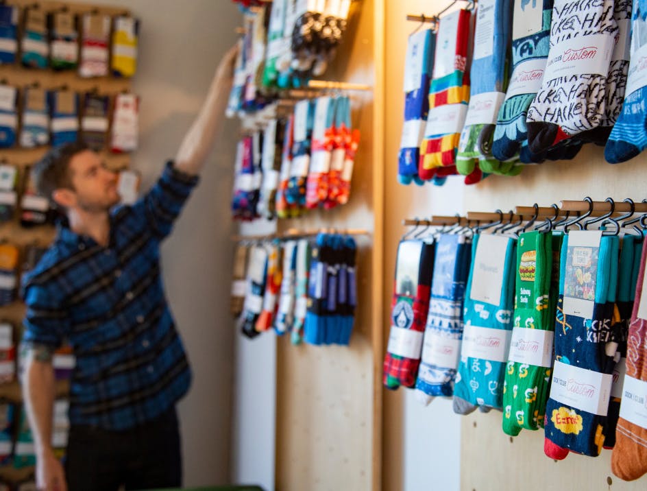sock club custom socks with logo hanging on wall and person looking at them