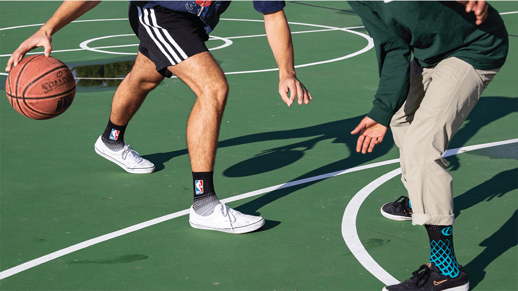 Two people playing basketball wearing black athletic socks