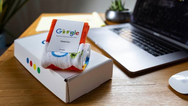 A corporate gift box from Google with a pair of branded socks sitting on a desk in a modern office