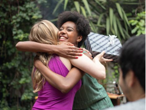 Two female best friends hugging and smiling