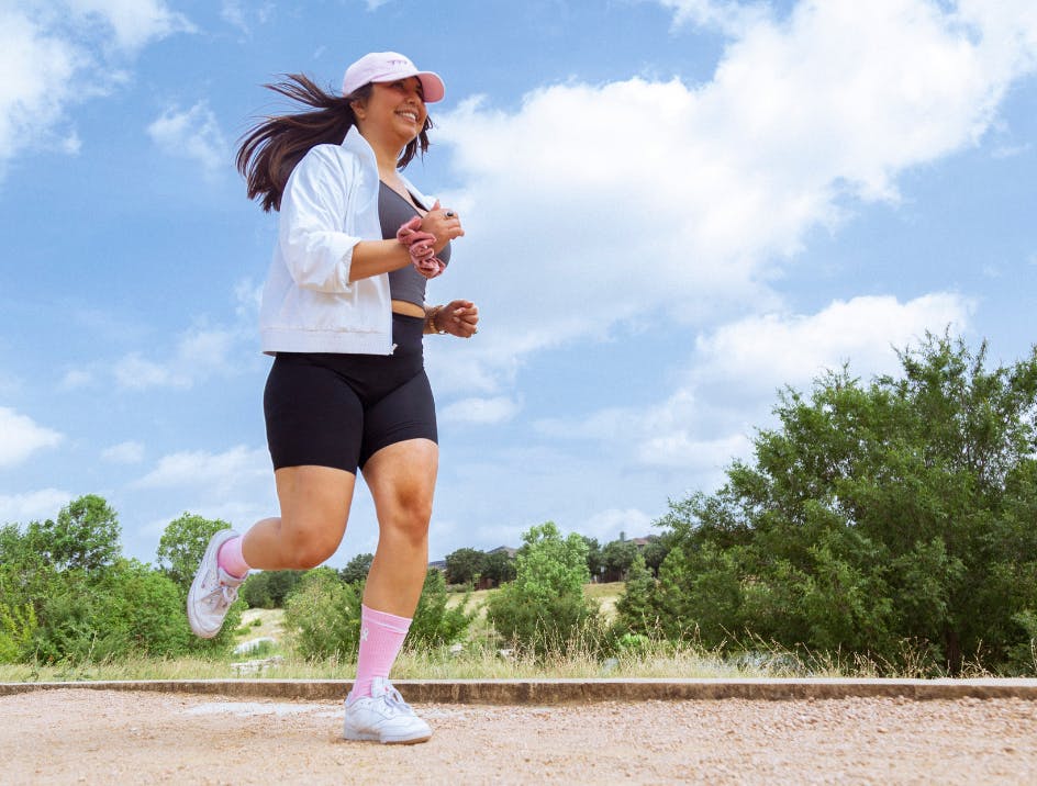 Person running wearing pink crew-length socks and white sneakers