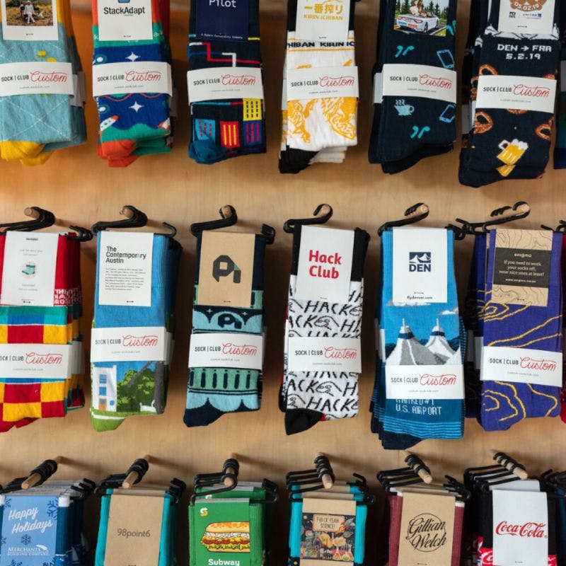 Merchandising display showing a number of custom socks designed for corporate merchandise hanging on the wall
