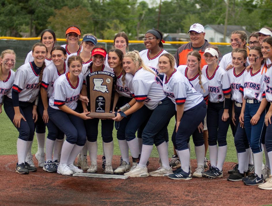 A champion softball team holding their trophy and wearing white knee high softball team socks