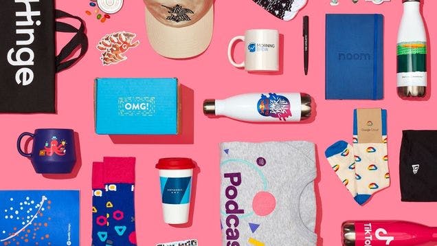 A variety of custom swag items like custom socks, notebooks, waterbottles, and t-shirts created for company swag stores by swag.com
