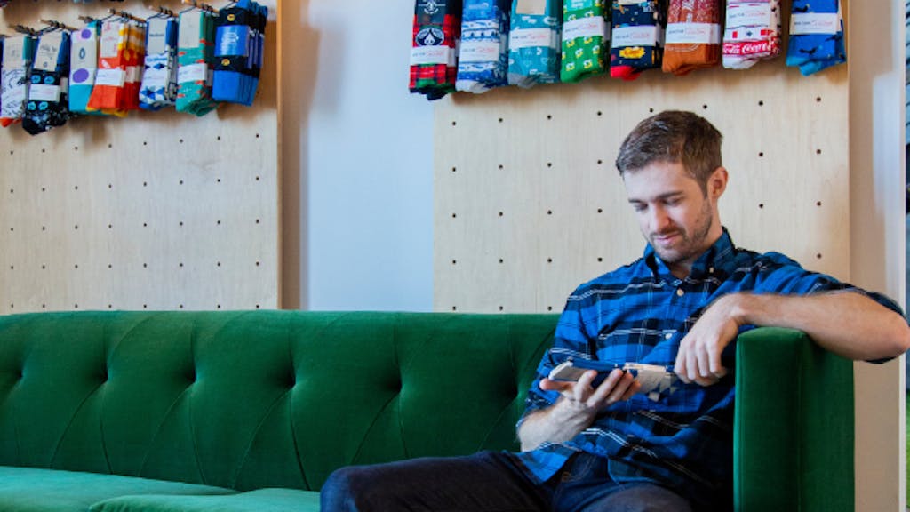 man looking at custom socks sitting on green couch