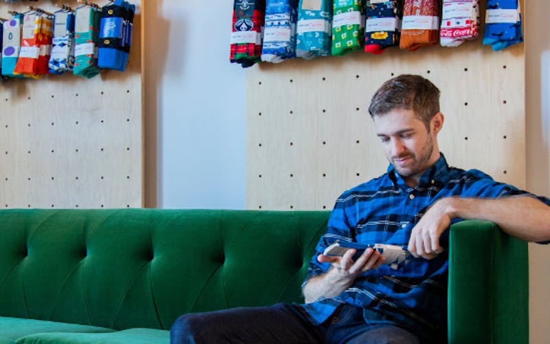 man looking at custom socks sitting on green couch