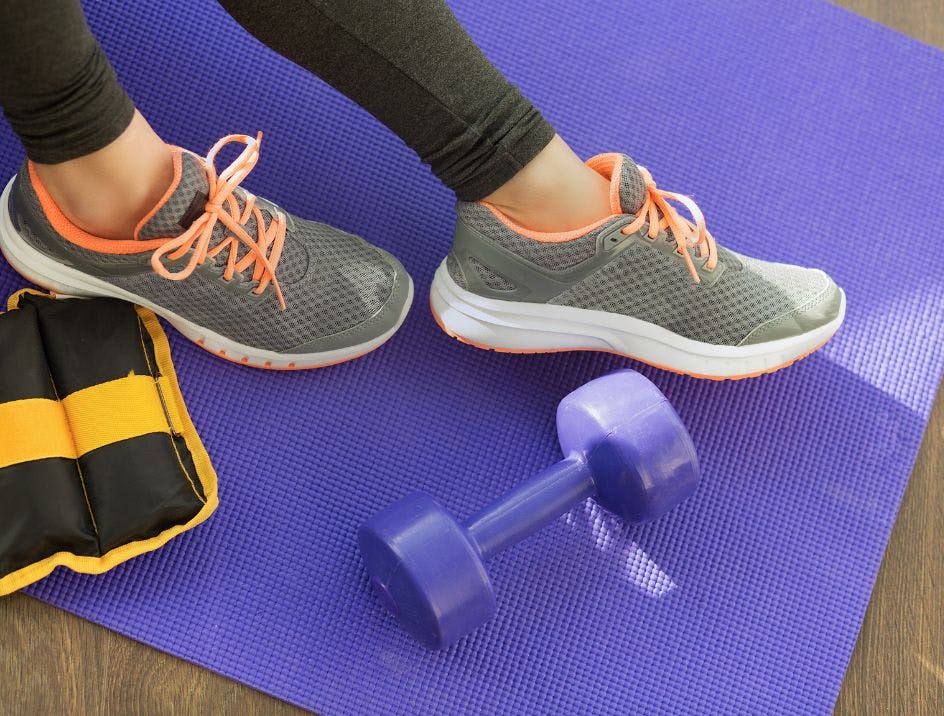 Woman wearing athletic shoes with no show athletic socks on a purple yoga mat in the gym
