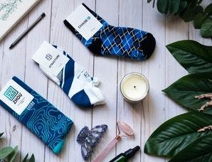 Three different custom socks used for donor gifts laid out on a table with candles and greenery