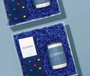 Custom polka dot socks for onna created by Sock Club for Palisades Canyon with a branded tumbler and blue crinkle paper in a corporate gift box