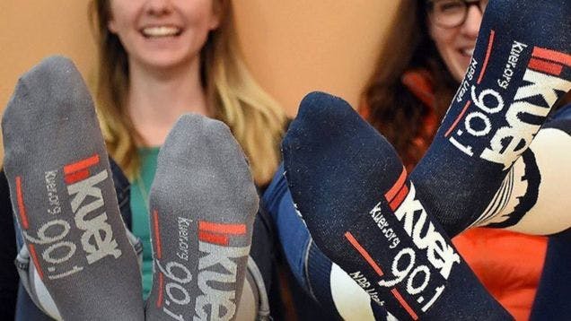 Volunteers for public radio station KUER showing off their custom socks that they got as a volunteer appreciation gift