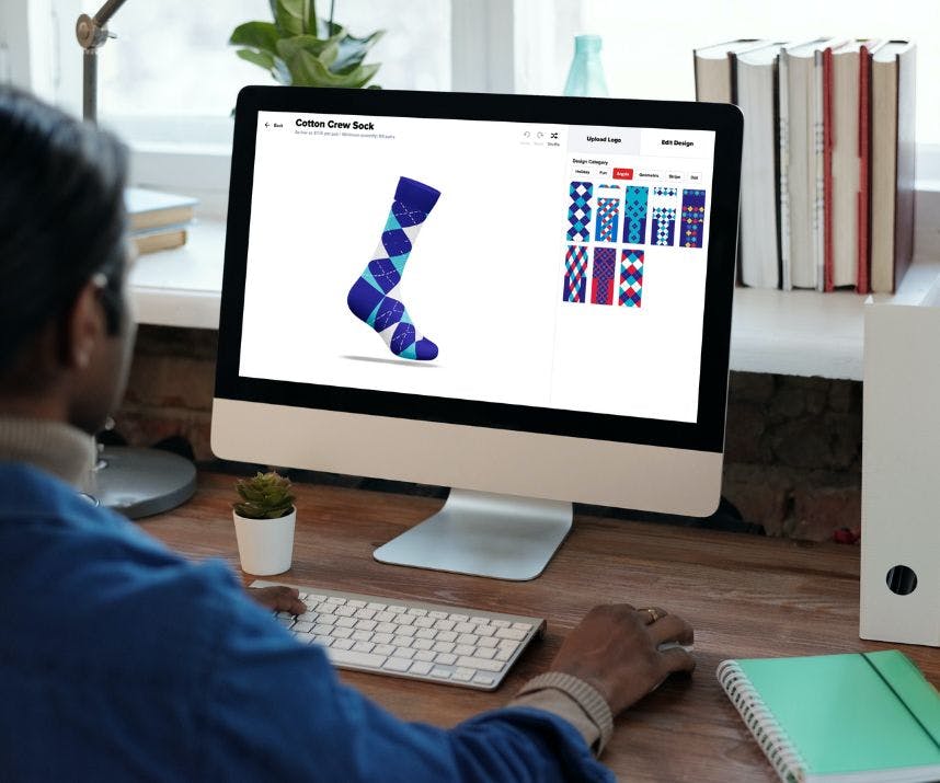 A man in his home office at a desk designing a custom sock with Sock Club's online sock design builder