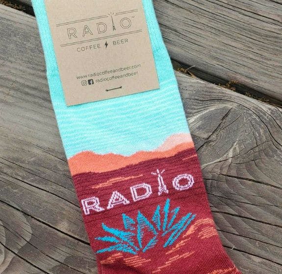 Custom socks for Radio Coffee and Beer showing a west Texas themed design in aqua, peach, and red