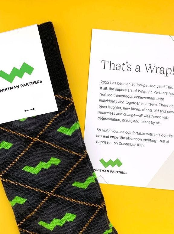 Custom socks for Whitman Partners on a yellow background with a thank you note