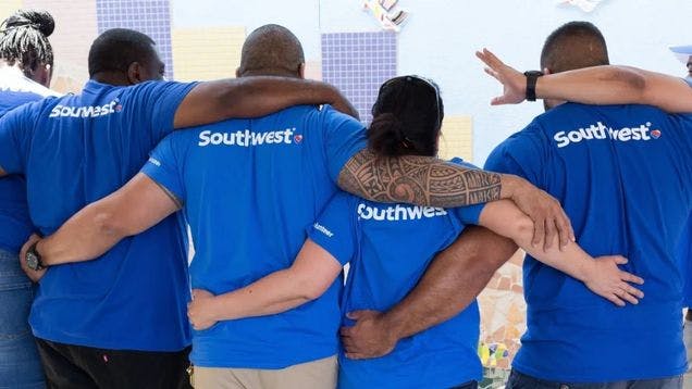 Southwest employees showing an example of positive company culture by wearing the brand t-shirt and putting their arms around each other