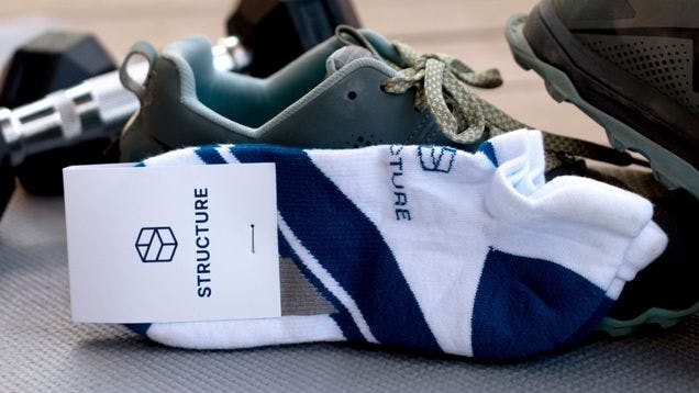 Custom athletic ankle sock on a gym floor with gym shoes and weights in the background
