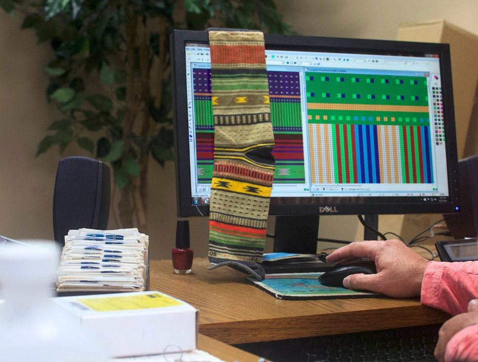 A member of Sock Club's manufacturing team programming a computer to knit the design that the design team made