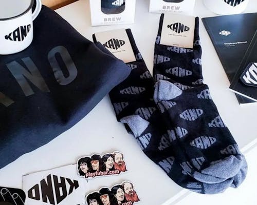 custom socks with logo of kano in black on table for conference giveaways