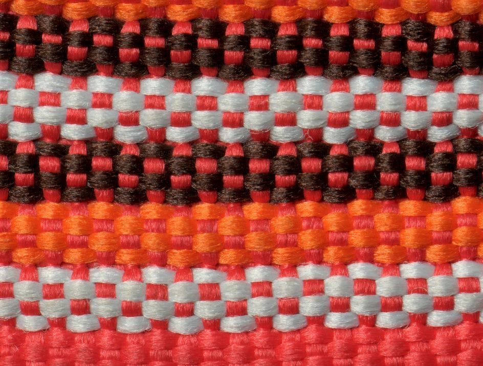 A woven strap made out of red, orange, black, and white fibers