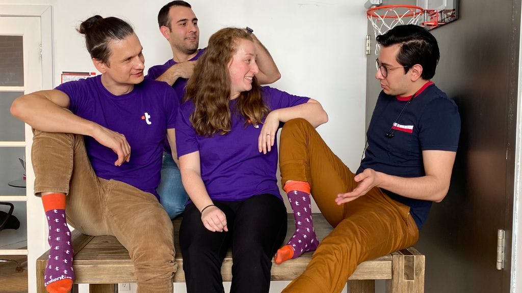 The Talent.com team showing off the custom socks they ordered from Sock Club in a casual office setting