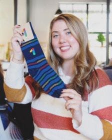 Happy employee holding up a branded sock that she got as an employee appreciation gift