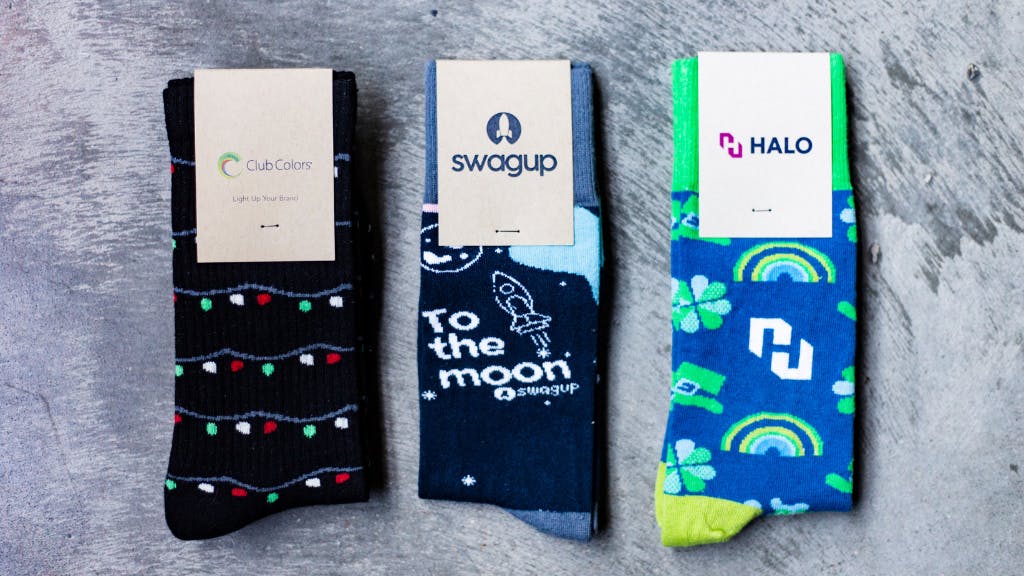 Black and blue custom socks with logos on grey background
