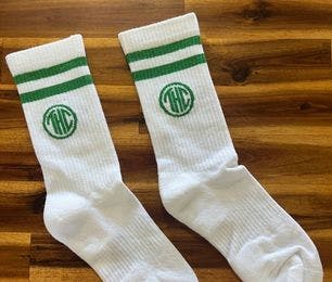 Branded white custom athletic socks for The Herban Cannasseur on a wooden background