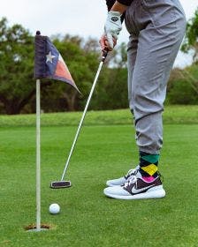 Custom argyle golf socks on a golfer putting into the hole on a green