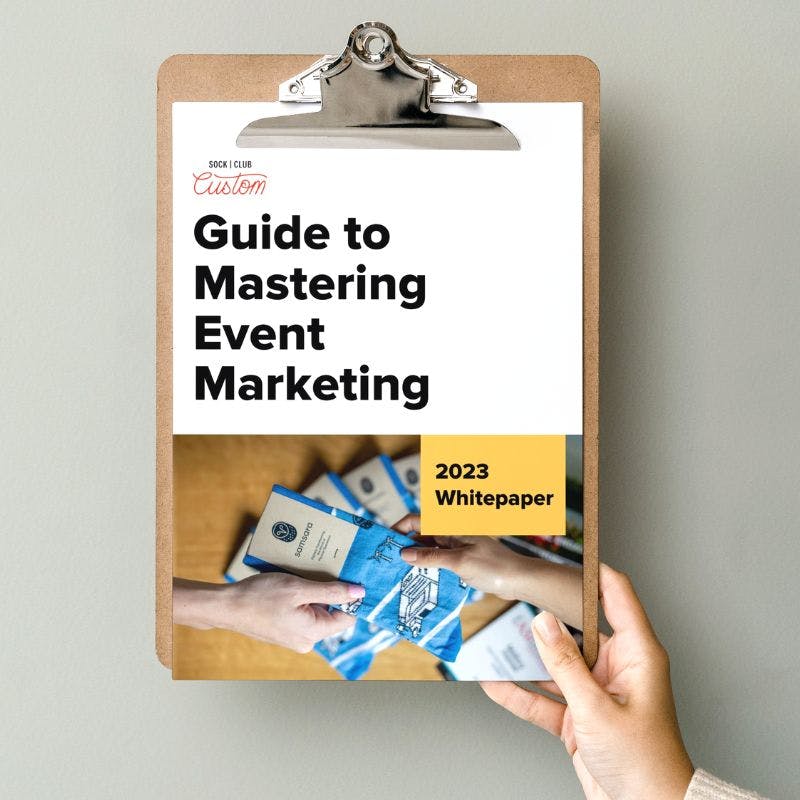 Woman holding up clipboard displaying Sock Club's Guide to Mastering Event Marketing