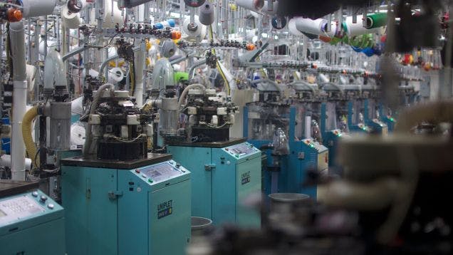 A row of sock knitting machines in Sock Club's custom sock manufacturing plant in North Carolina
