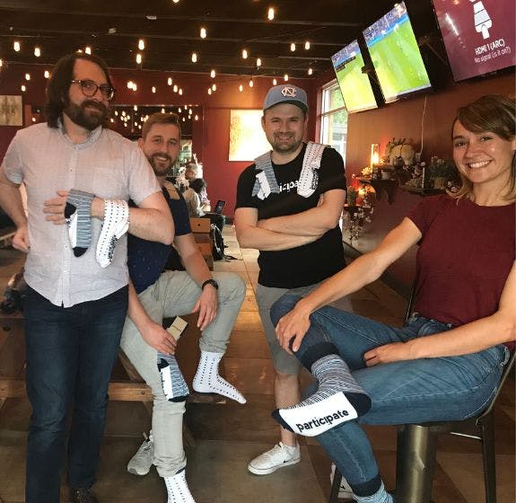 The Participate team at their quarterly meeting showing of the branded socks from Sock Club that they received from Sock Club as employee appreciation swag