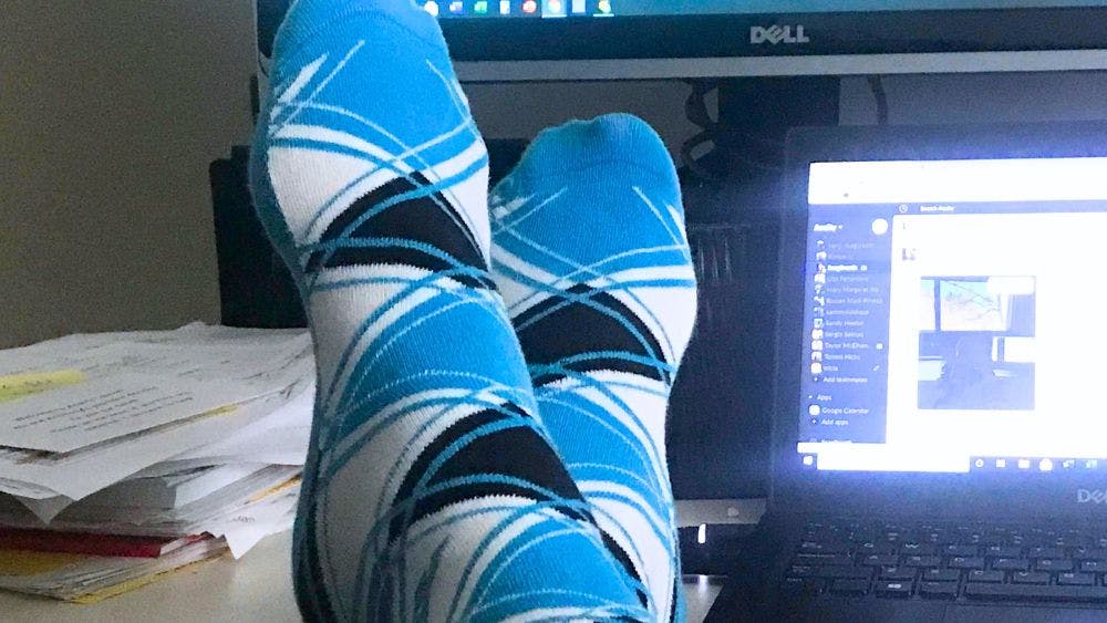 Custom argyle socks for Acuity being worn by a remote employee with his feet up on his desk