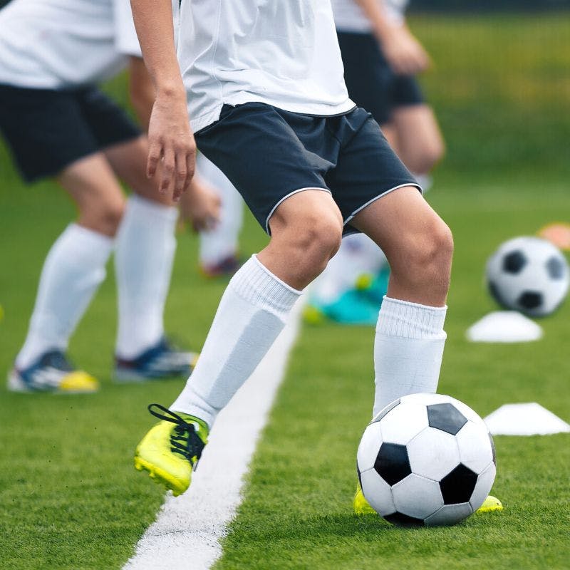 A soccer player wearing custom soccer socks kicking the ball in soccer practice