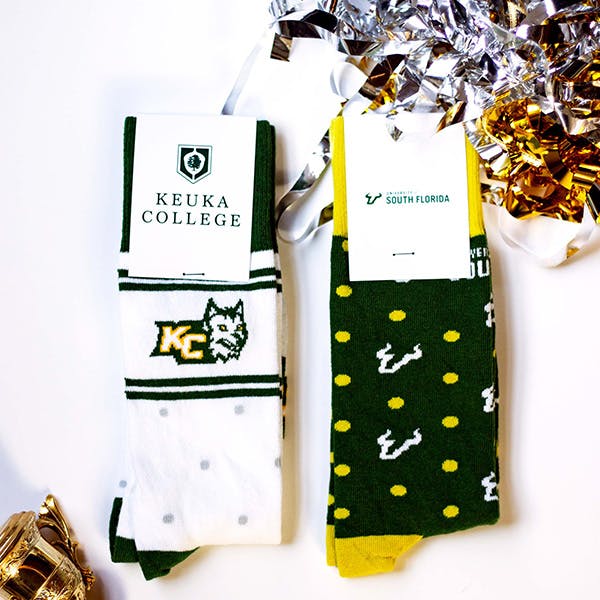 Green, white, and yellow custom team socks with silver and gold pom poms in the background 