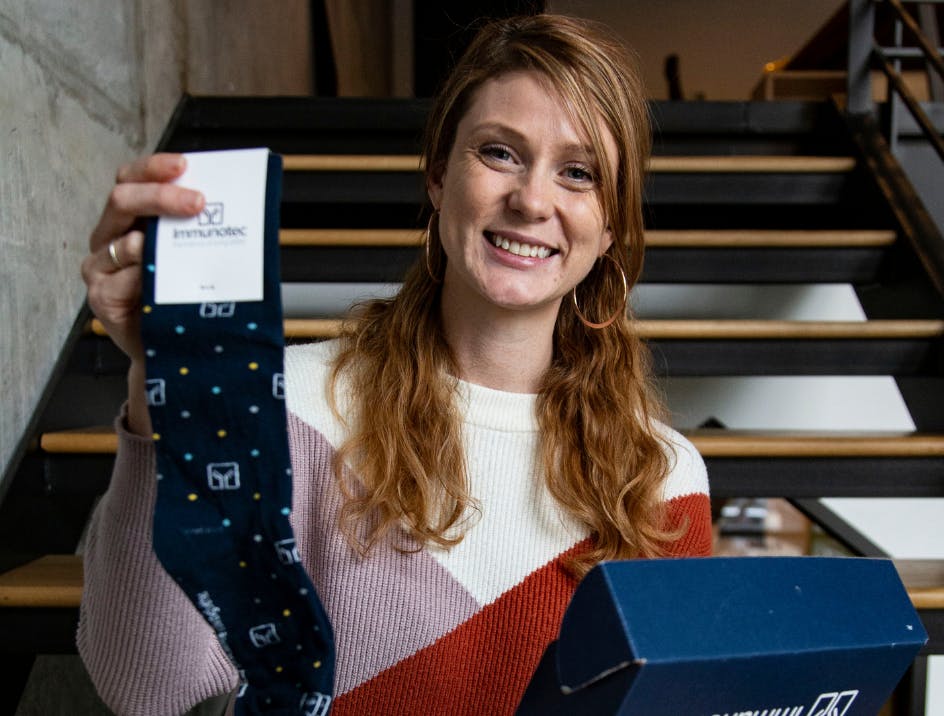 Person holding navy blue custom logo socks and smiling 