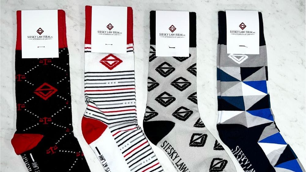 Four different custom sock designs that Siesky Law ordered to give out as corporate gifts to clients
