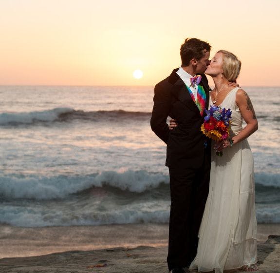 Bride and Groom Kissing on a Beach at sunset with the waves in the background