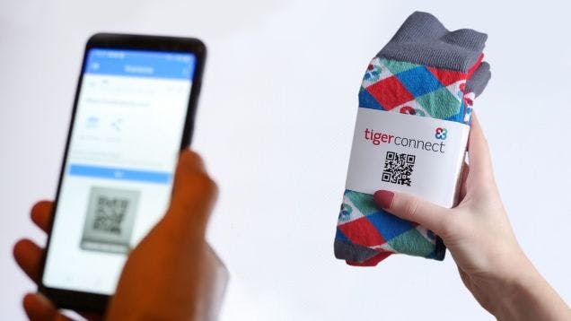 Manicured hand holding a custom branded logo sock created for tigerconnect with a custom middle wrap displaying a QR code