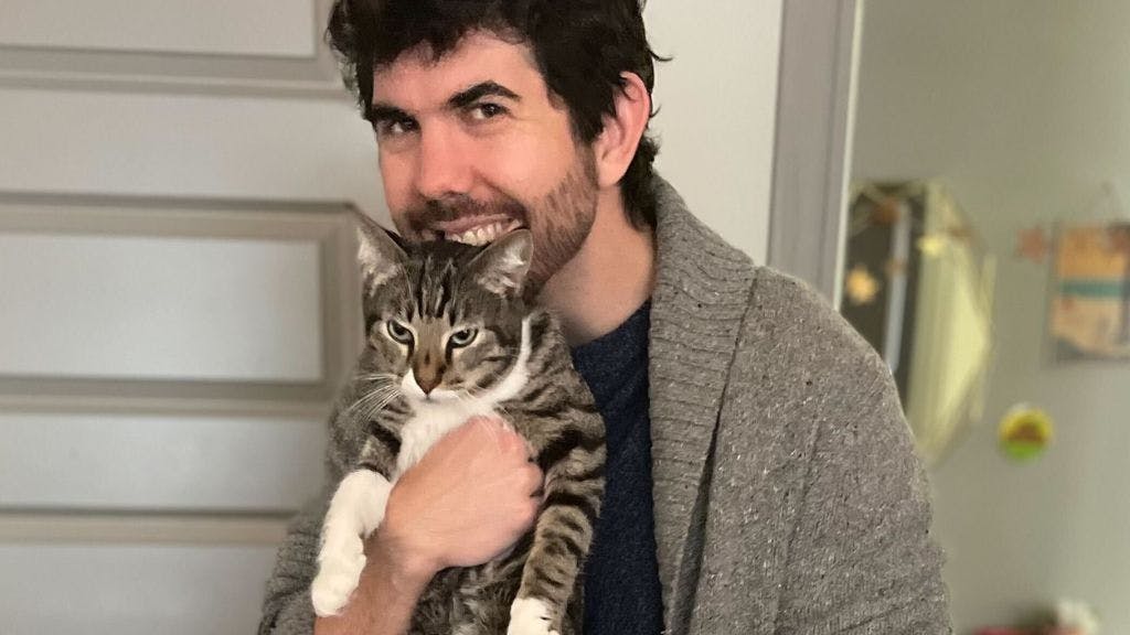 Sales Operations Manager Ryan Wood holding his pet cat and smiling