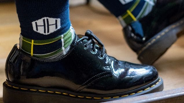 High quality branded merchandise as custom socks shown with dress shoes in an office