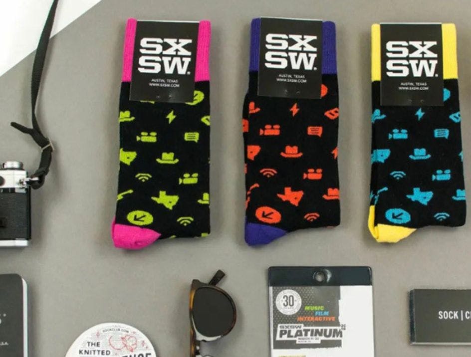 Custom socks for SXSW with a full bleed being shown with some music festival essentials, such as sunglasses, a badge, and a camera