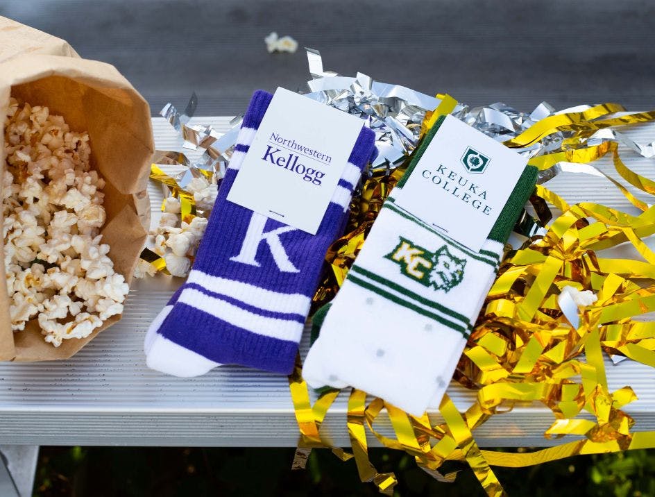 Custom football socks for Northwestern Kellogg University and Keuka College on a set of bleachers with popcorn