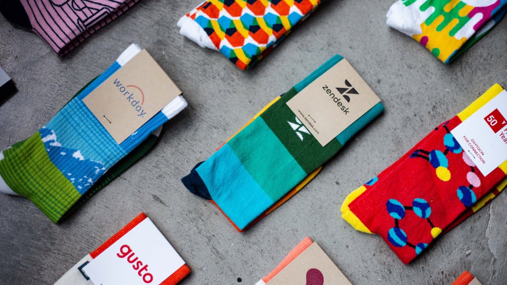 custom socks with logo over concrete desk with zendesk socks gusto socks and workday socks