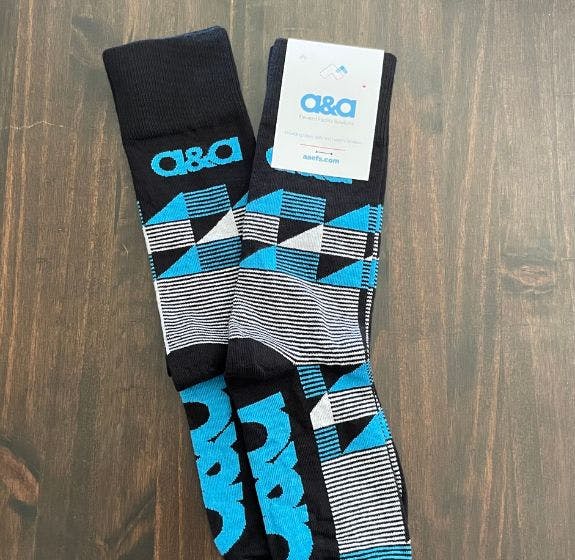 Custom socks for A&A Elevated Facility Solutions that have a striped pattern on them in blue and white with the company logo