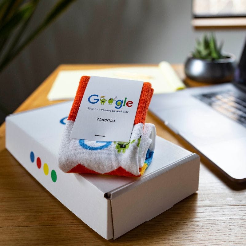 A corporate gift box from Google with a pair of branded socks sitting on a desk in a modern office