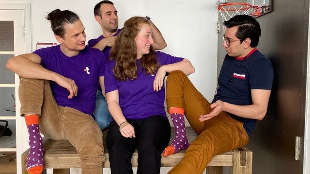 The Talent.com team showing off the custom socks they ordered from Sock Club in a casual office setting