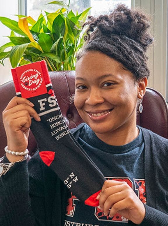 Alumni donation coordinator holding up custom socks that she ordered for a Giving Day campaign targeted at college alumni