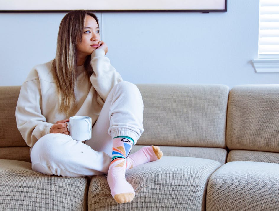 Person sitting on couch in comfy clothes wearing Sock Club custom socks